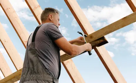 builder-working-on-a-wooden-roof-frame-against-the-sky
