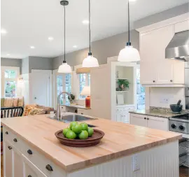 cozy-kitchen-with-wood-countertops-white-cabinets-and-pendant-lights.