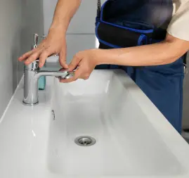 plumber-is-installing-a silver-faucet-on-a-white sink